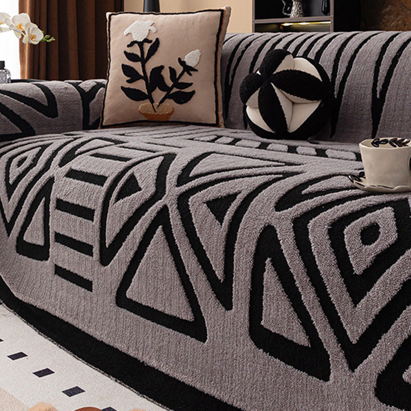 Grauer Bezug mit schwarzem geometrischem Muster aus Dreiecken und Rauten, dazu ein Kissen mit Blumenmotiv 15