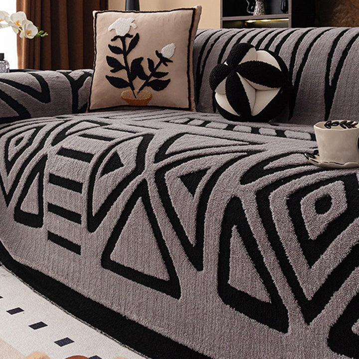 Grauer Bezug mit schwarzem geometrischem Muster aus Dreiecken und Rauten, dazu ein Kissen mit Blumenmotiv 15