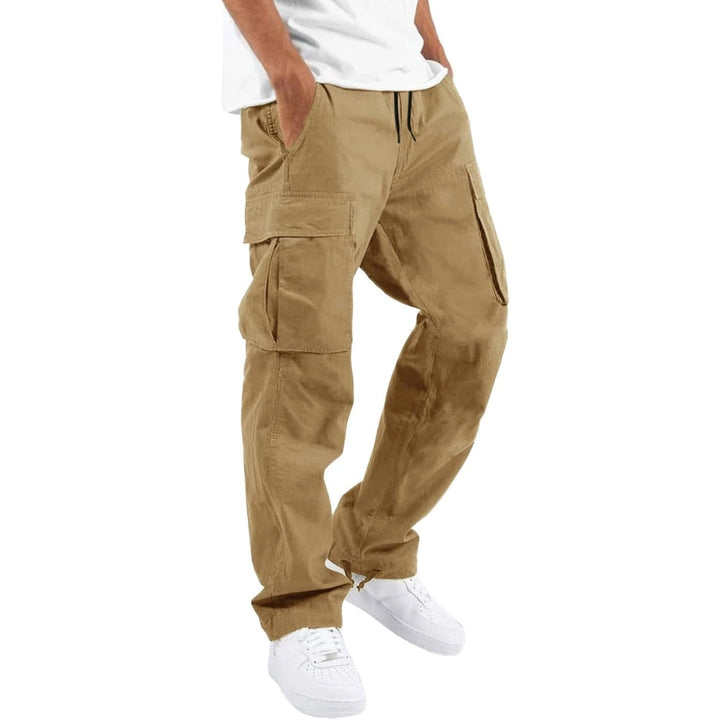 Model trägt die Cargohose in sandfarbenem Khaki mit Kordelzug und aufgesetzten Seitentaschen, kombiniert mit weißem T-Shirt und weißen Sneakern. 7