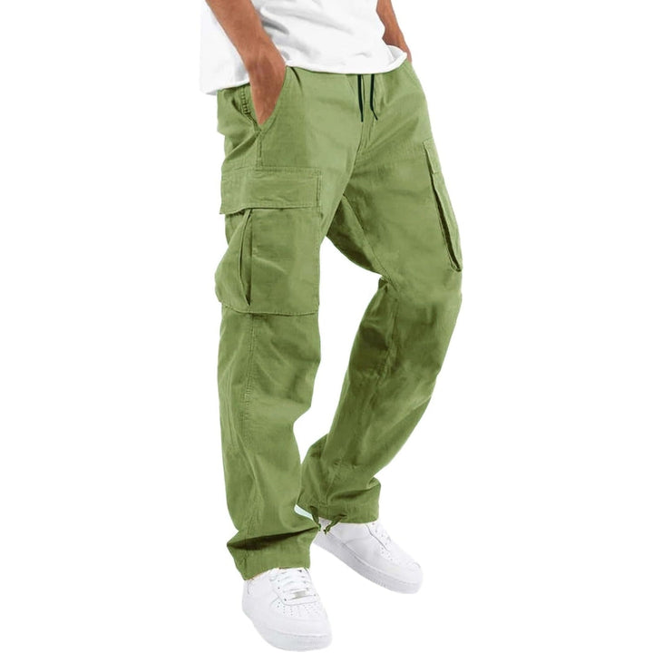 Model trägt die Cargohose in hellem Grün mit Kordelzug und Seitentaschen, Hände in den Taschen, dazu weißes T-Shirt und weiße Sneaker. 9