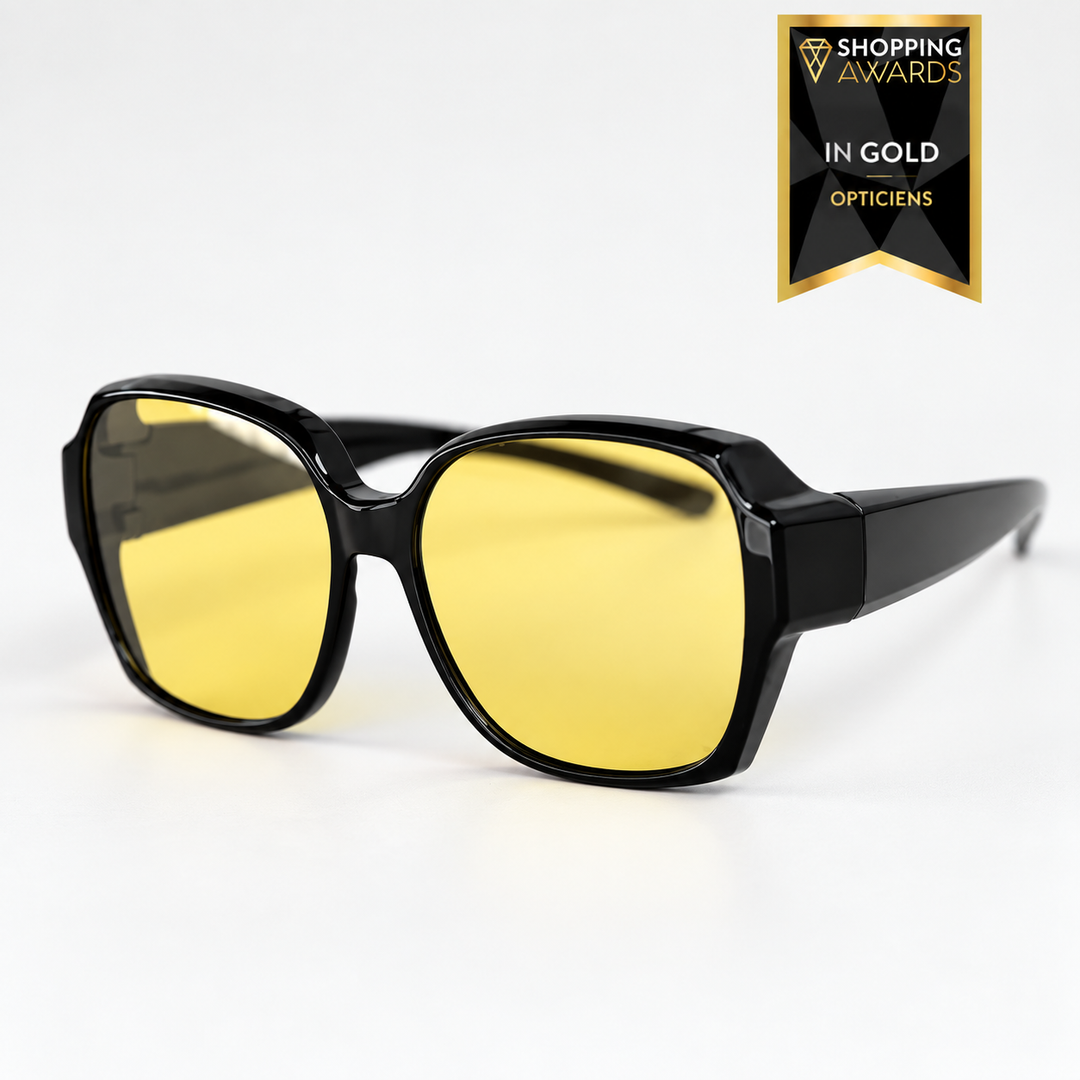 Große Überzieh-Nachtfahrbrille mit glänzend schwarzem Rahmen und gelben Gläsern, schräg von vorn auf hellem Hintergrund. 1