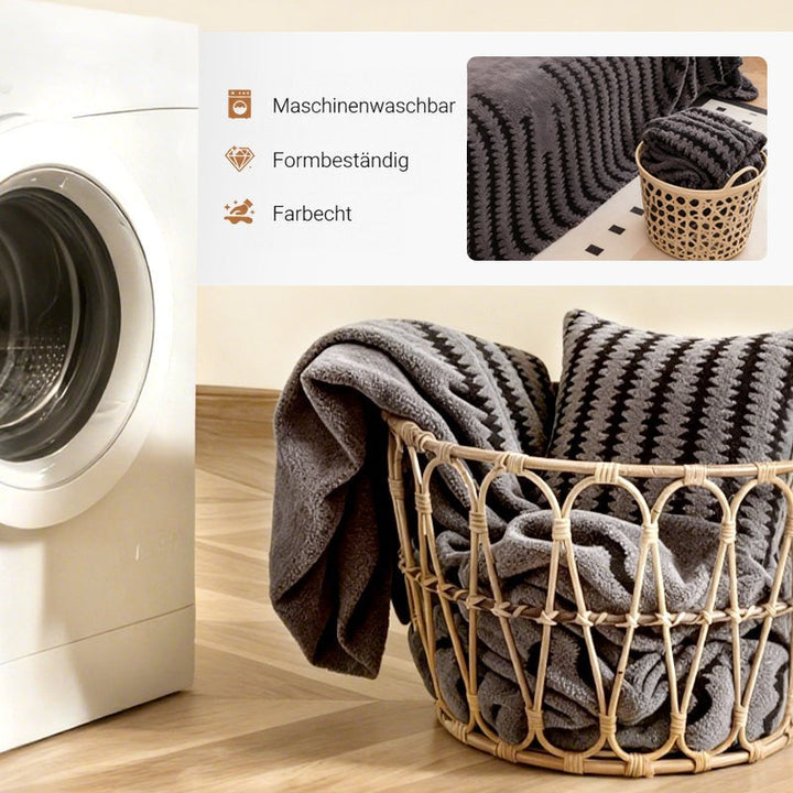 Grauer gemusterter Bezug und Kissen in einem Rattankorb neben einer Waschmaschine, Nahaufnahme des Bezugs oben rechts 5