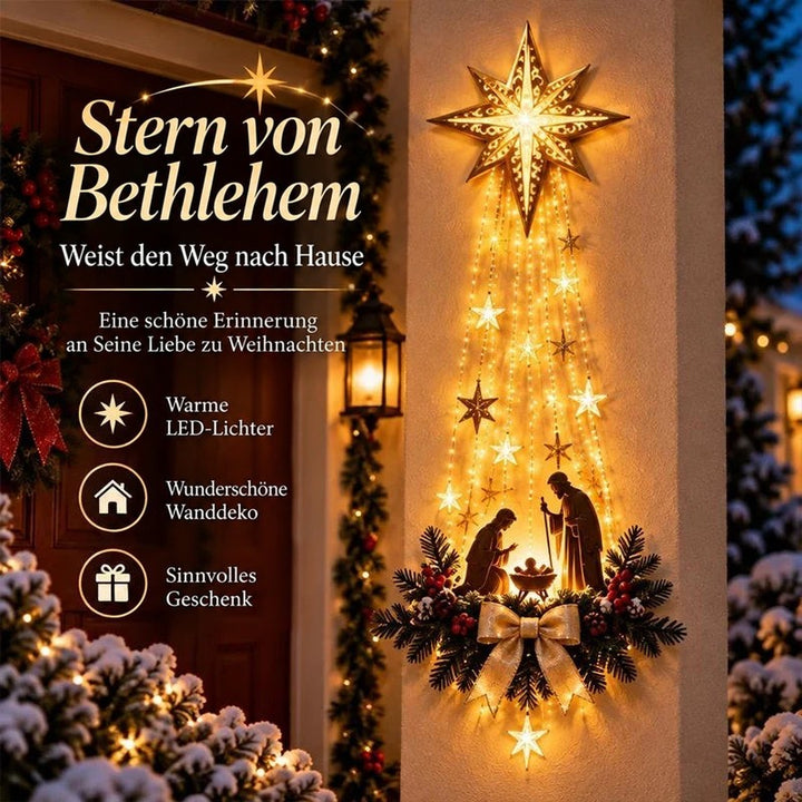 Leuchtender Stern mit Lichterkaskade und Krippenszene an einer Hauswand neben der Tür, abends mit Schnee 1