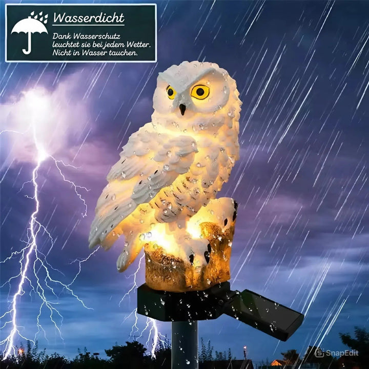 Leuchtende weiße Eulenfigur auf Baumstumpf mit Erdspieß und Solarpanel, bei Gewitter und Regen mit Wassertropfen auf dem Harz. 1