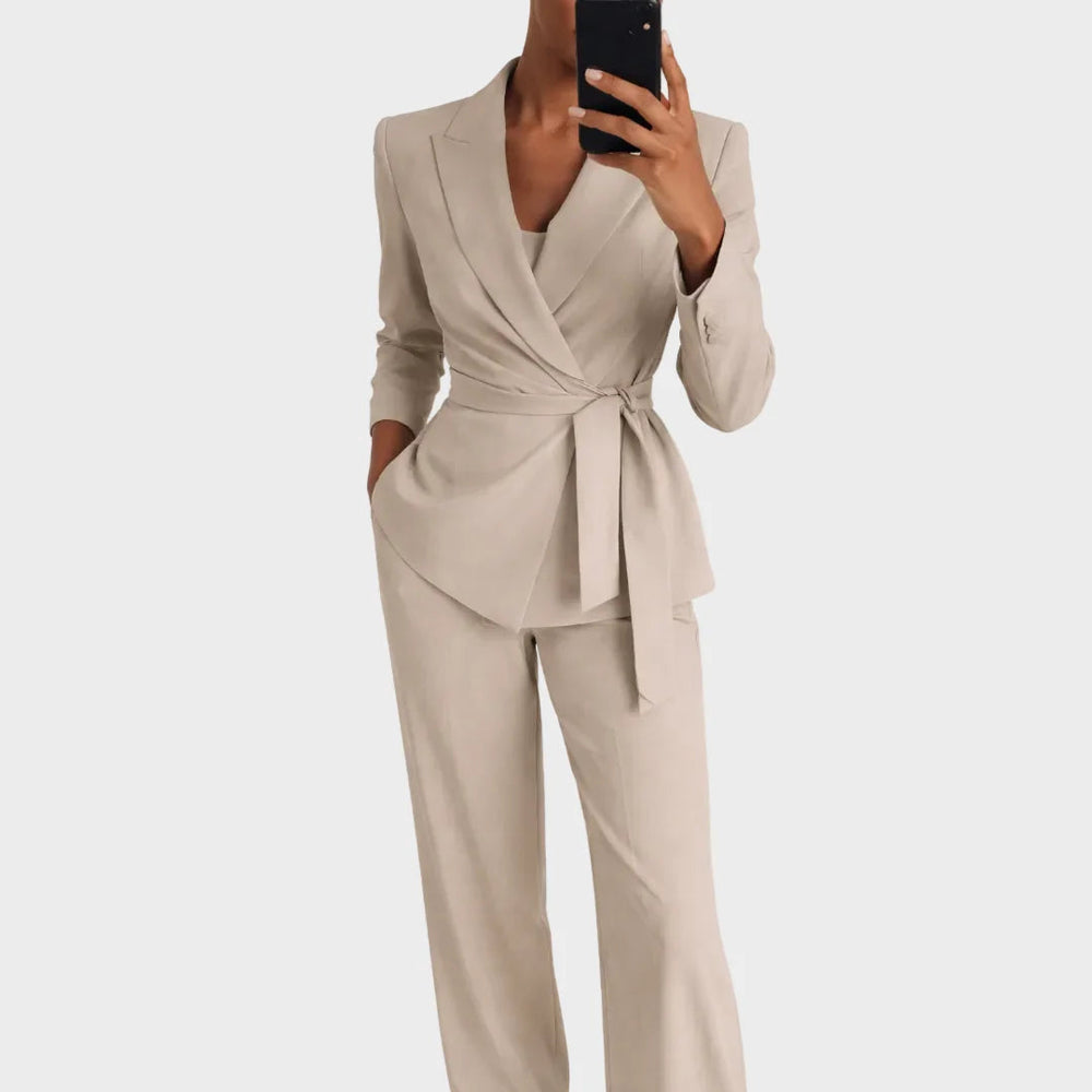 Das Set in Beige: Wickelblazer mit Gürtelschleife und weite Hose, Frontansicht, Model hält beim Spiegelfoto eine Hand in der Tasche. 2