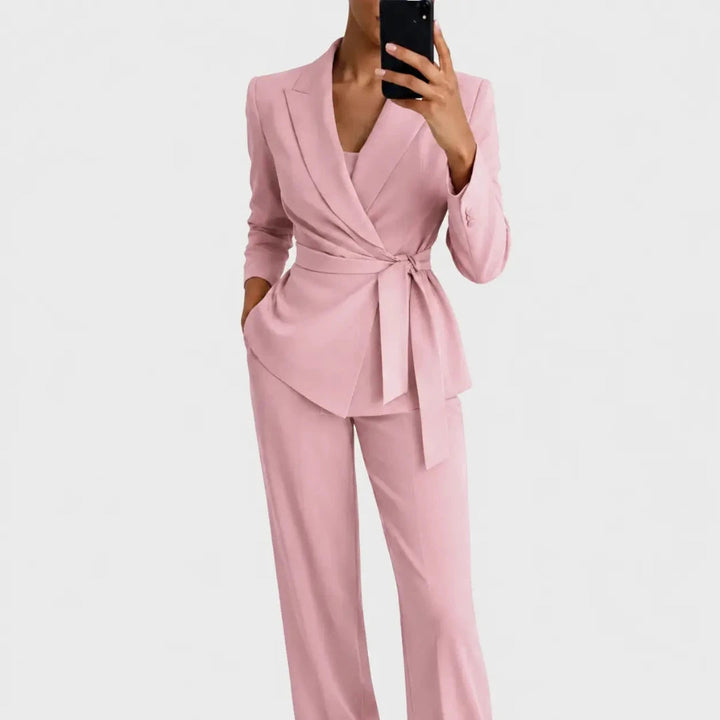 Das Set in Rosa: Wickelblazer mit Schleifengürtel und weit geschnittene Hose, Frontansicht, Model macht ein Spiegelfoto mit dem Smartphone. 4