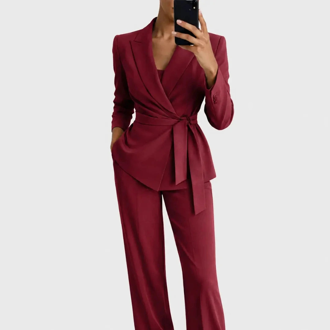 Das Set in Weinrot: Blazer mit Wickeloptik und Bindegürtel, dazu weite Hose, Frontansicht, Model hält ein Handy vor das Gesicht. 5