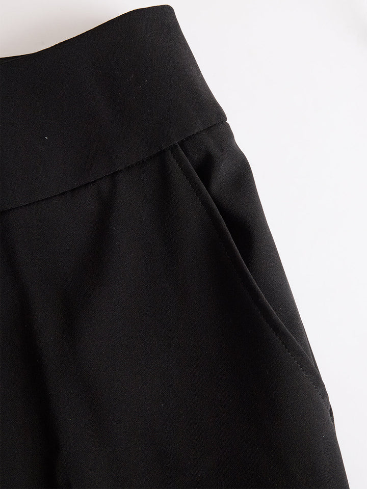 Detailansicht des breiten Bundes und der seitlichen Eingrifftasche der schwarzen Hose, flach auf weißem Hintergrund fotografiert. 5