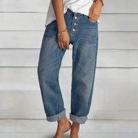 Frau in blauen Boyfriend-Jeans, gekrempelt, lässiger Stil, weiße Bluse, Holzarmband.