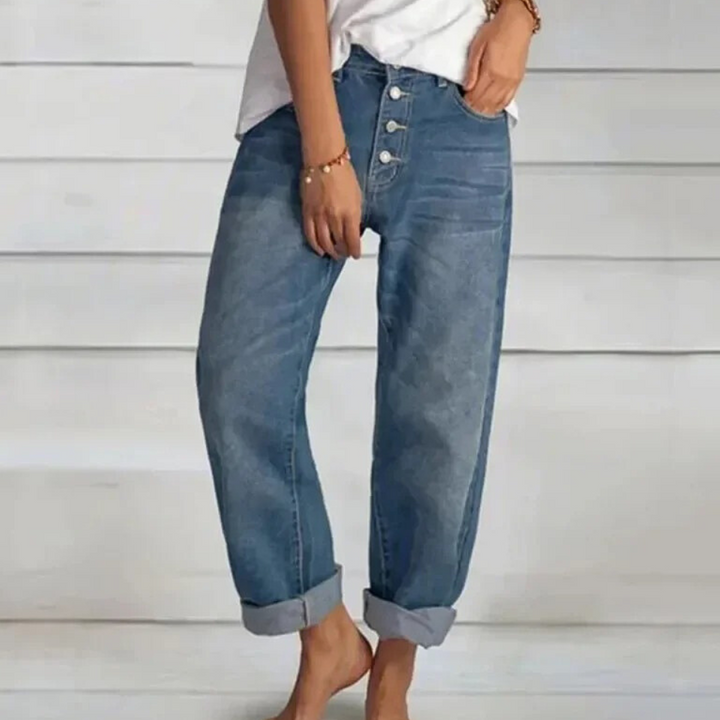 Frau in blauen Boyfriend-Jeans, gekrempelt, lässiger Stil, weiße Bluse, Holzarmband.