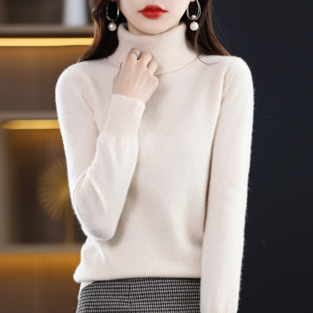 Cremeweißer Rollkragenpullover am Model, eine Hand am Kragen, kombiniert mit kariertem Rock. 15