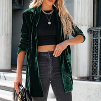 Frau in dunkelgrünem Samtblazer, schwarzem Top und Jeans, modisch, urbaner Stil.