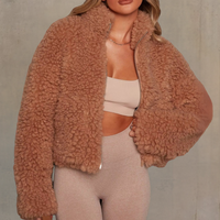 Frau in brauner Teddyfelljacke, beige Top und Leggings, modische Winterkleidung, gemütlich.