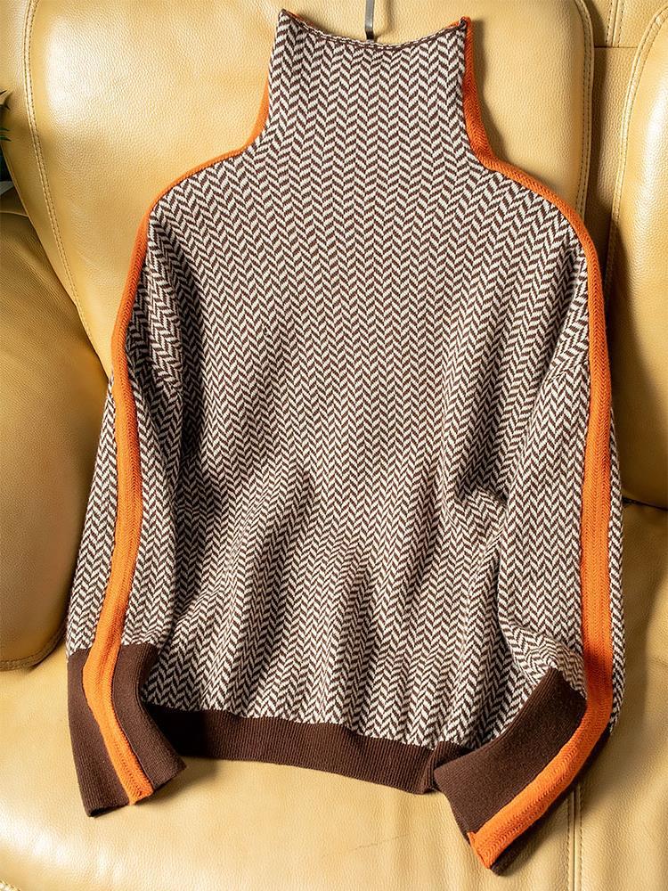 Flach auf einem hellen Ledersessel ausgebreiteter Pullover in Fischgrätmuster mit hohem Kragen, orangefarbenen Seitenstreifen und braunen Bündchen. 4