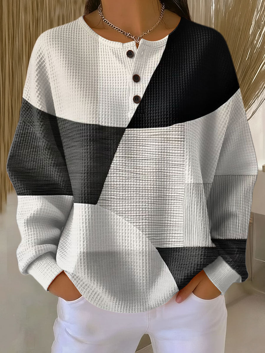 Getragener Pullover mit Knopfleiste im schwarz-weiß-grauen Patchwork-Design aus geometrischen Flächen. 2