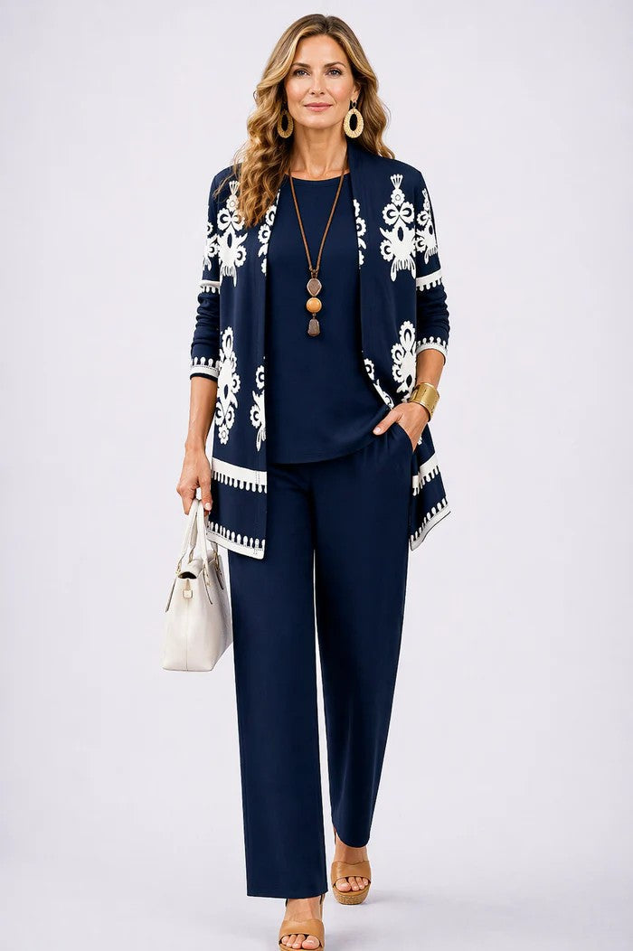 Frau im marineblauen Set, Cardigan mit weißem Ornamentmuster und Zierborte über Oberteil und Hose, Hand in der Tasche. 14