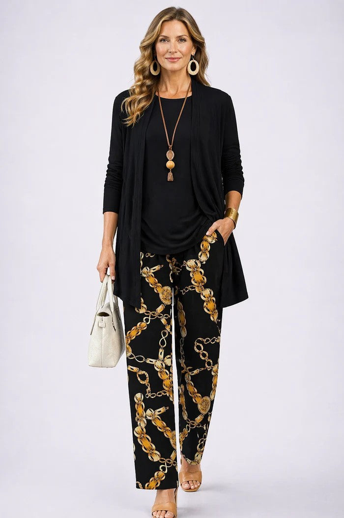 Frau im Set mit schwarzem Cardigan und Oberteil, dazu schwarze Hose mit goldenem Kettenmuster, frontal. 17