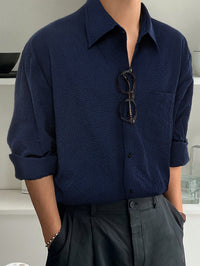 Mann in dunkelblauem Hemd mit Brille, lässiger Stil, moderne Herrenmode.