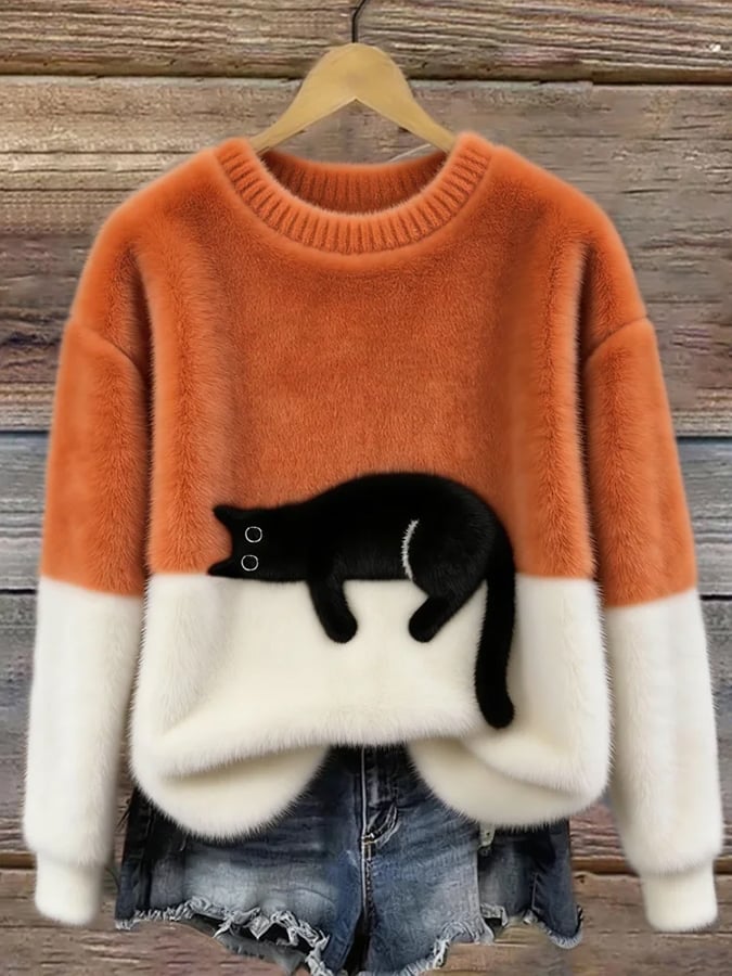 Flauschiger Pullover in Orange mit weißem Unterteil und aufgenähter schwarzer Katze, an Holzbügel vor Holzwand 3