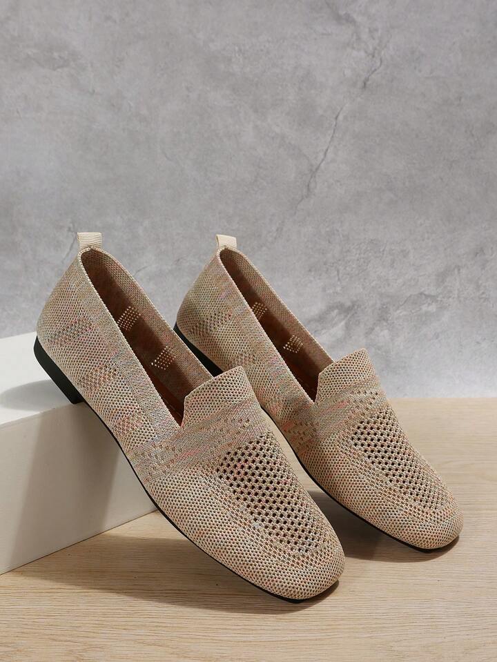 Beige melierte Slip-ons mit Lochmuster am Vorderfuß, an einem weißen Block angelehnt, vor grauer Wand. 7