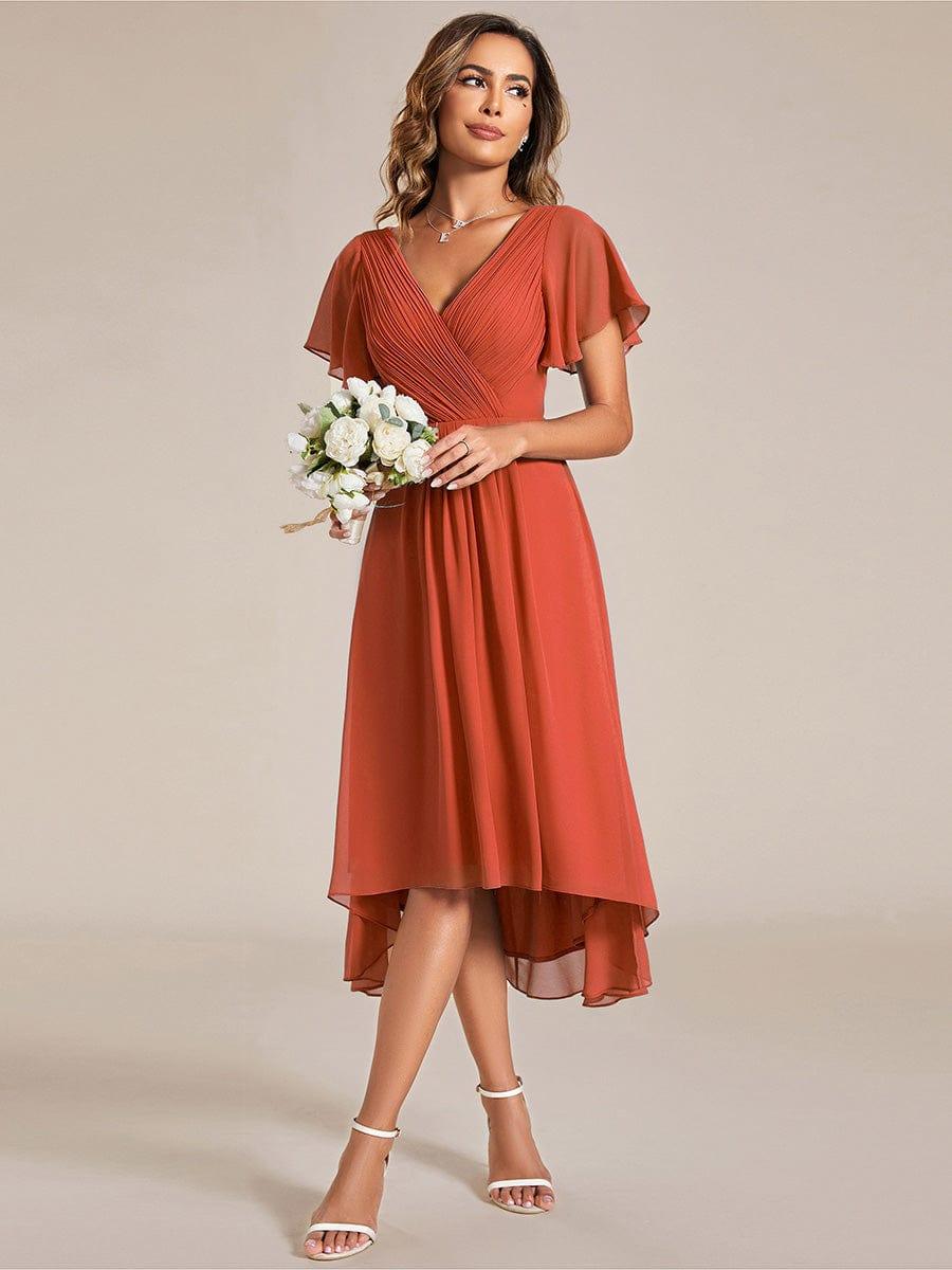 Model in terrakottafarbenem Kleid hält einen Strauß weißer Blumen, Blick zur Seite, dazu weiße Riemchensandaletten. 95