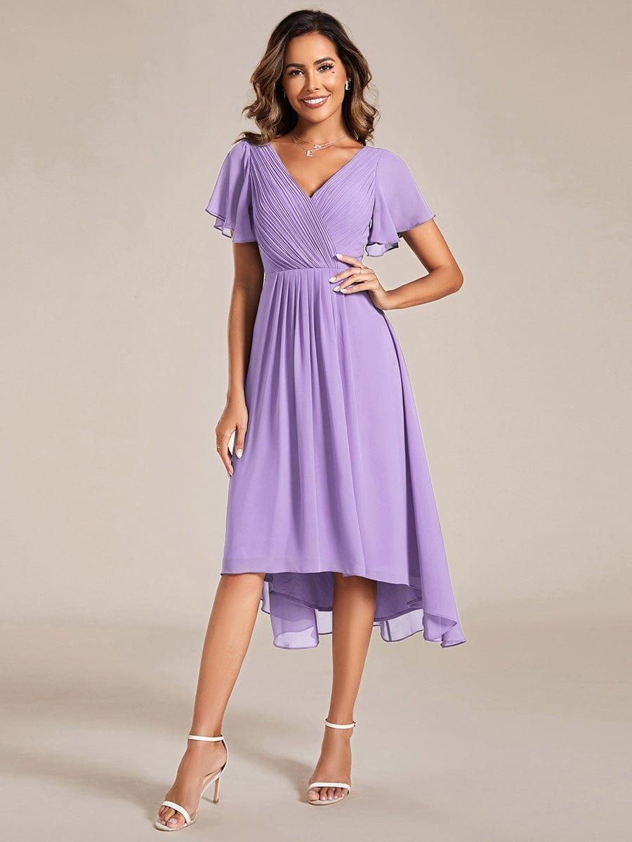Model in fliederfarbenem Chiffonkleid mit Plisseeoberteil, V-Ausschnitt, Flatterärmeln und Hoch-Tief-Saum, Hand an der Hüfte. 100