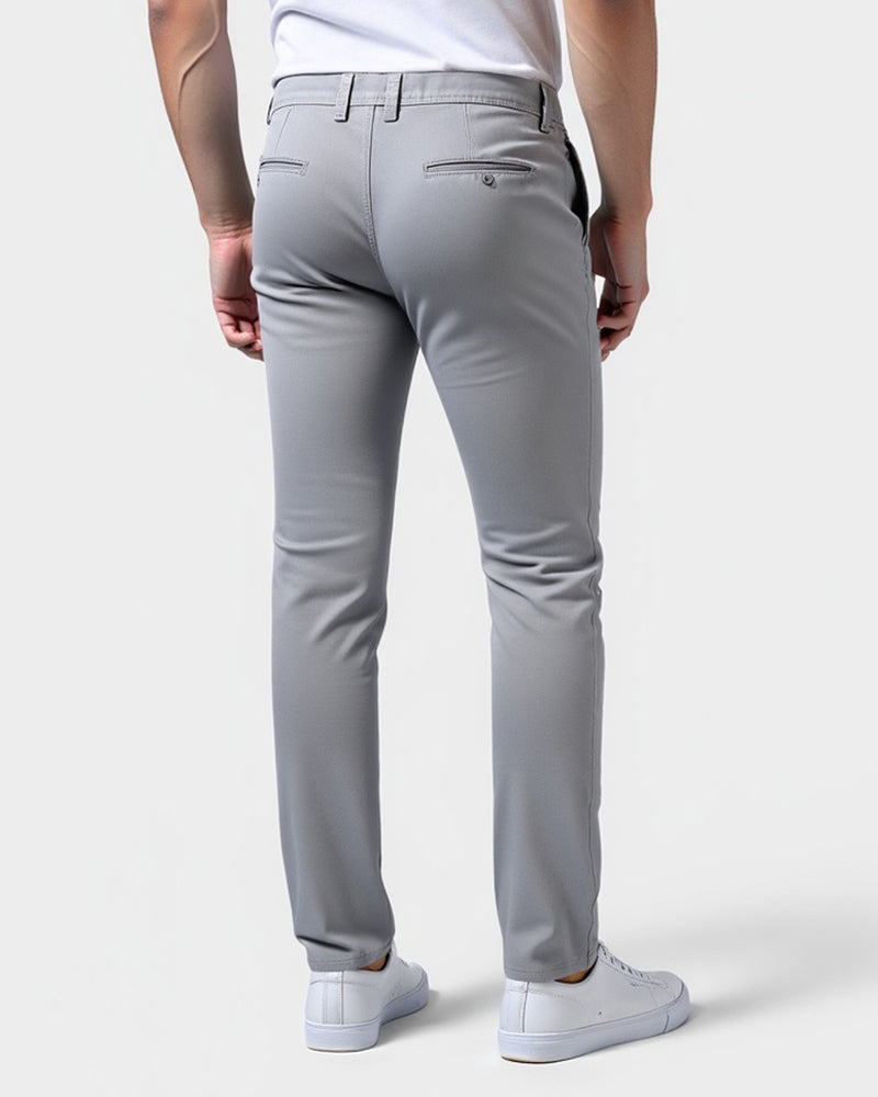 Rückansicht der hellgrauen Chino mit aufgesetzten Gesäßtaschen mit Knopf, dazu weißes Shirt und weiße Sneaker. 3