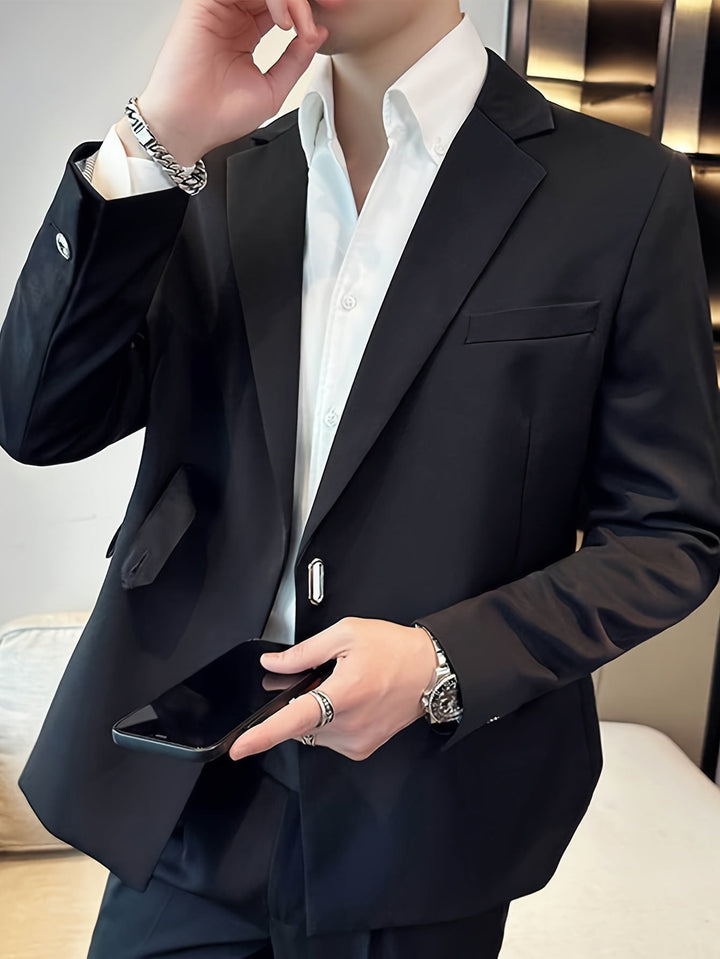 Mann im eleganten schwarzen Anzug mit weißem Hemd, hält Smartphone, trägt Armbanduhr und Ringe.