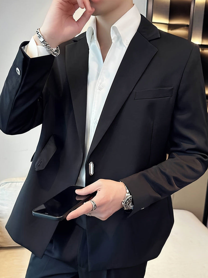 Mann im eleganten schwarzen Anzug mit weißem Hemd, hält Smartphone, trägt Armbanduhr und Ringe.