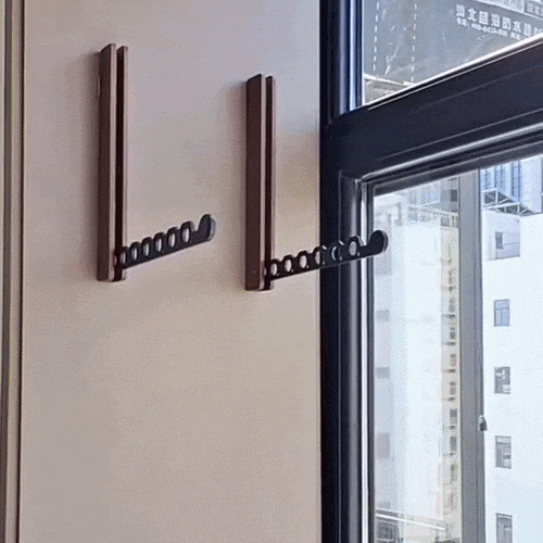 Zwei braune Wandhalterungen mit ausgeklapptem schwarzem Locharm neben einem Fenster, einer davon nah am Fensterrahmen montiert. 2