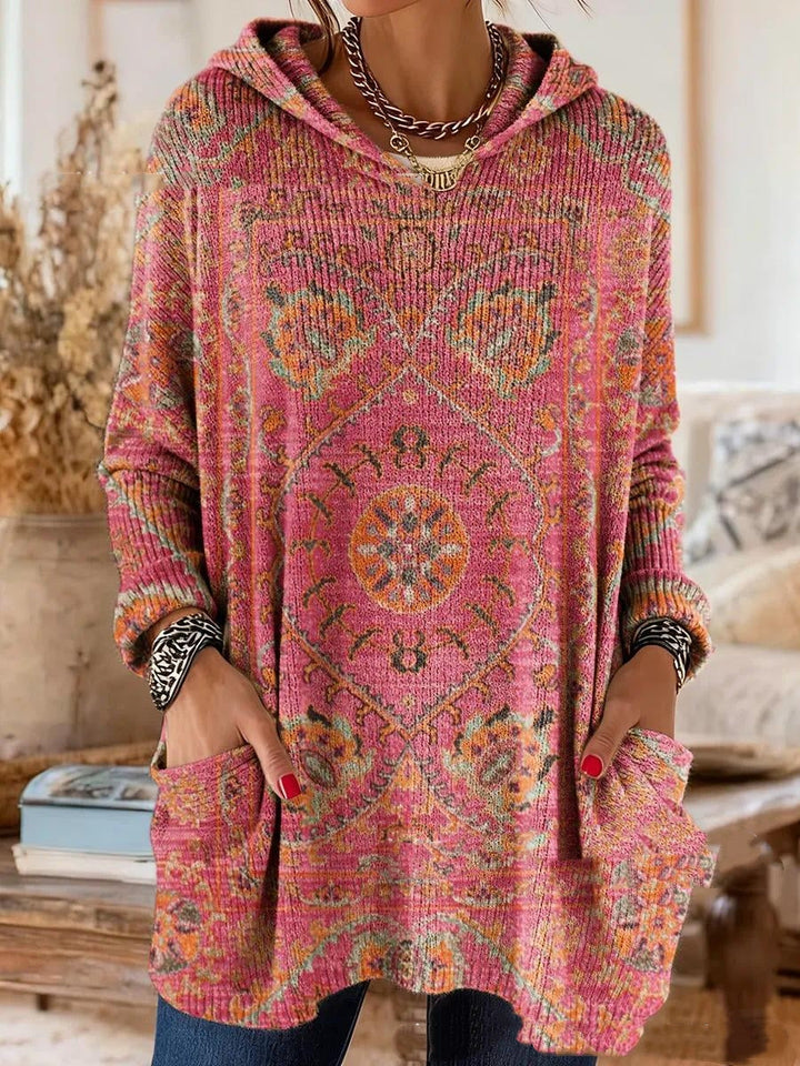 Getragene Kapuzentunika in Pink mit orangefarbenem und grünem Ornamentmuster, Hände in den Taschen, Nahaufnahme der Vorderseite. 6