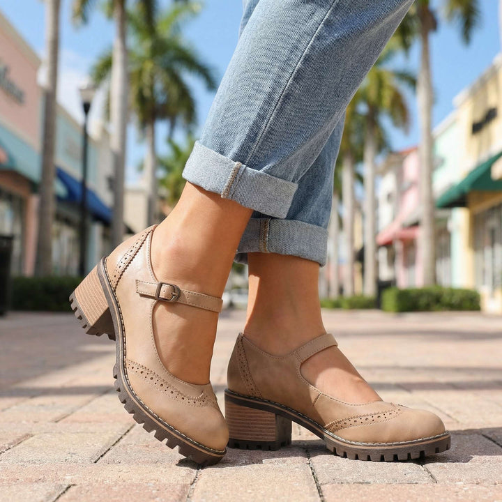 Beige Mary Janes mit Lochmuster und Blockabsatz, zu umgeschlagener Jeans auf einer sonnigen Einkaufsstraße mit Palmen getragen. 6