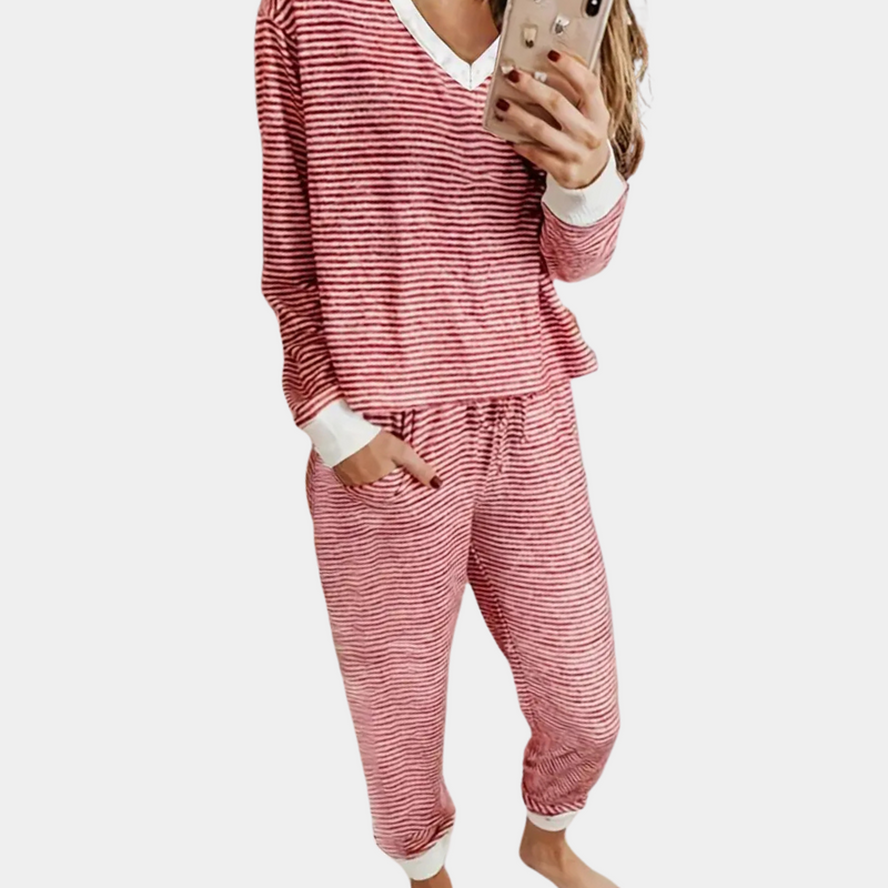 Frau in rot-weiß gestreiftem Pyjama, hält Smartphone, gemütliche Nachtwäsche, Baumwolle.