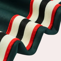 Grüner Stoff mit roten, schwarzen und weißen Streifen, Textilmaterial, Modeaccessoire.