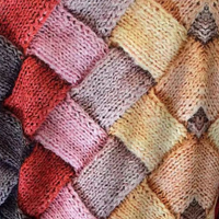 Bunte Strickdecke mit Zopfmuster, handgefertigt aus Wolle, Patchwork-Design, gemütlich und warm.