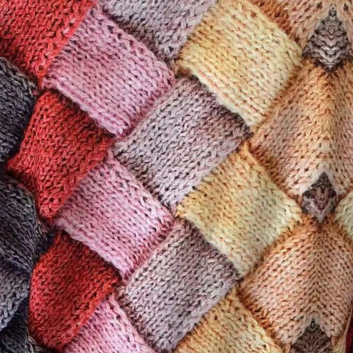 Bunte Strickdecke mit Zopfmuster, handgefertigt aus Wolle, Patchwork-Design, gemütlich und warm.