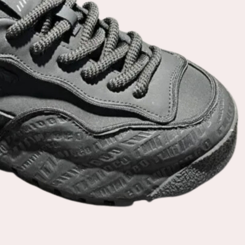 Schwarzer Sneaker mit geprägter Sohle, sportliches Design, Nahaufnahme, modisch, Unisex.