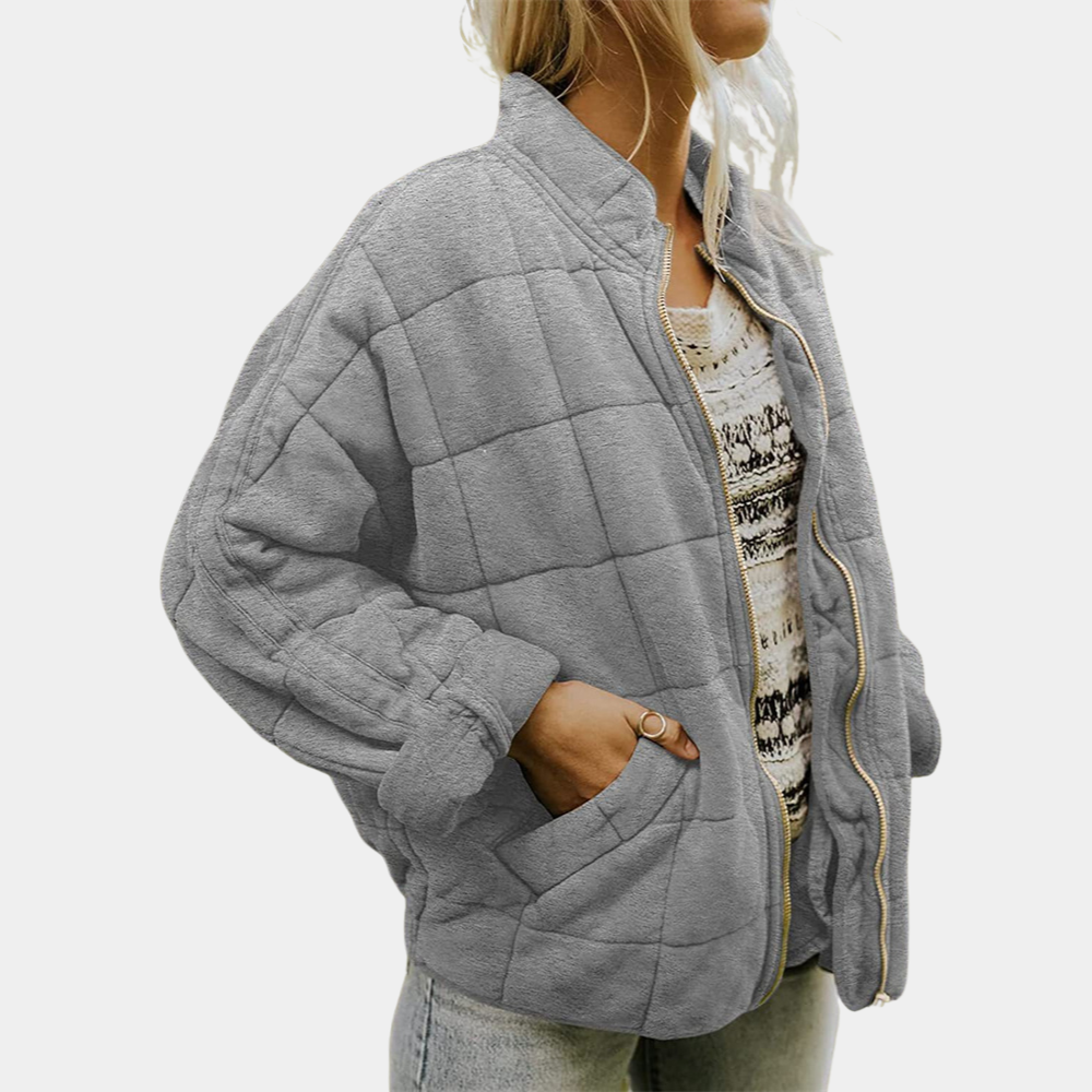 Frau trägt graue gesteppte Jacke, lässig, warm, modisch, ideal für Herbst und Winter.