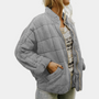 Frau trägt graue gesteppte Jacke, lässig, warm, modisch, ideal für Herbst und Winter.