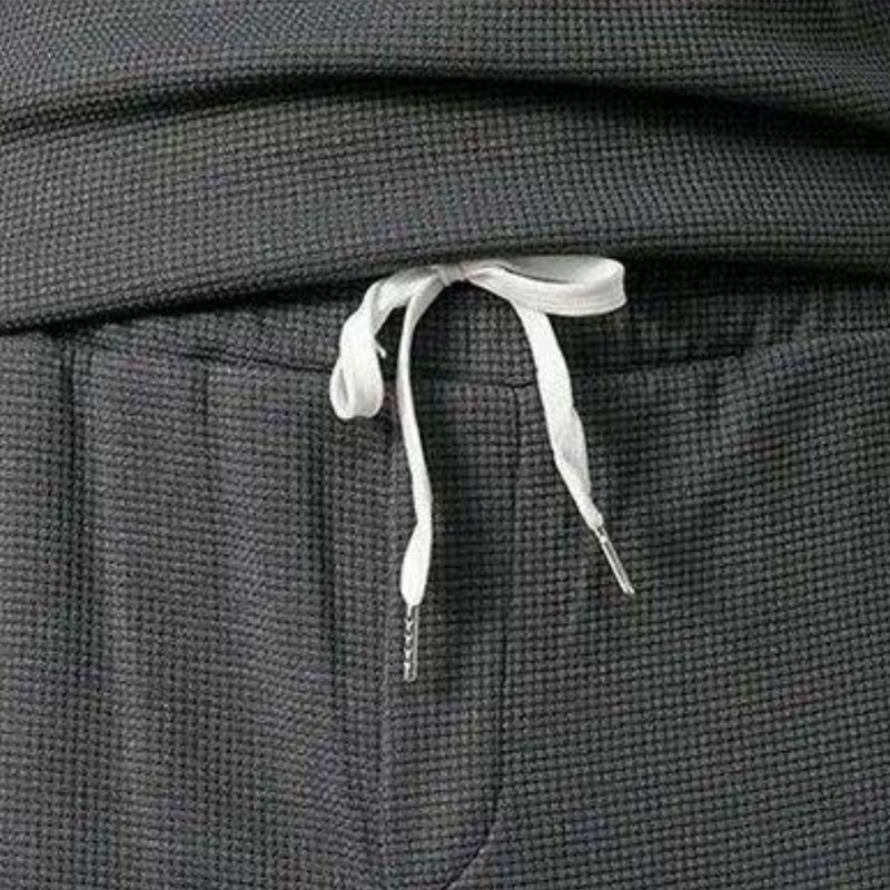 Graue Jogginghose mit weißem Kordelzug, Waffelstruktur, bequeme Freizeitkleidung.