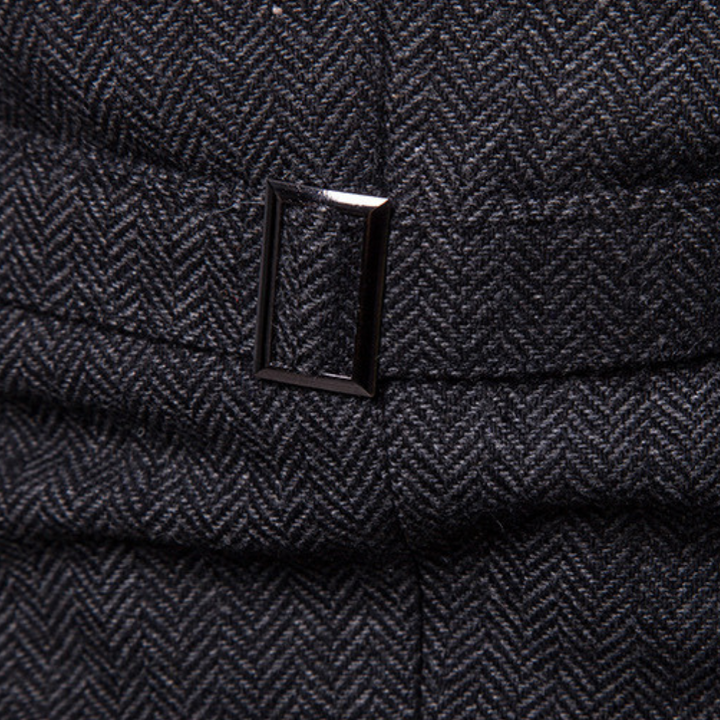 Dunkelgrauer Tweed-Stoff mit Fischgrätmuster und rechteckiger Metallschnalle.