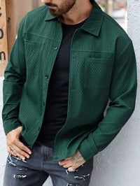 Mann in grüner Steppjacke, schwarzem T-Shirt und grauer Jeans mit Rissen, lässiger Streetwear-Look.