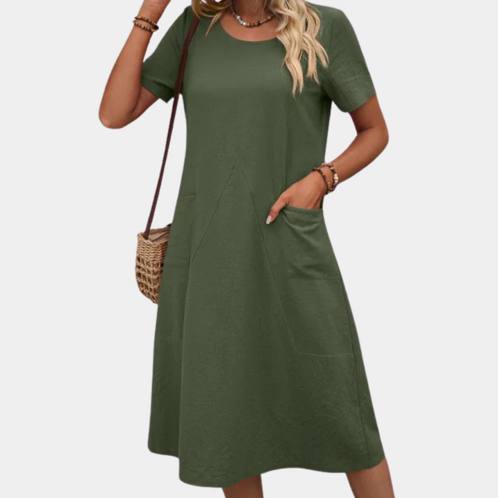 Frau in grünem Sommerkleid mit kurzen Ärmeln und Taschen, Strohtasche, lässiger Stil.