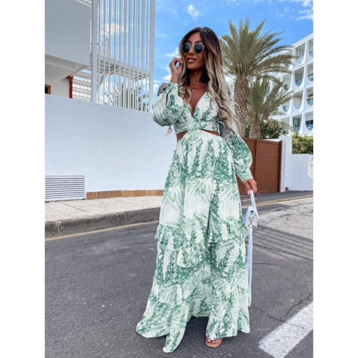 Frau in langem, grünem Sommerkleid mit Blattmuster, Sonnenbrille, draußen, modisch.