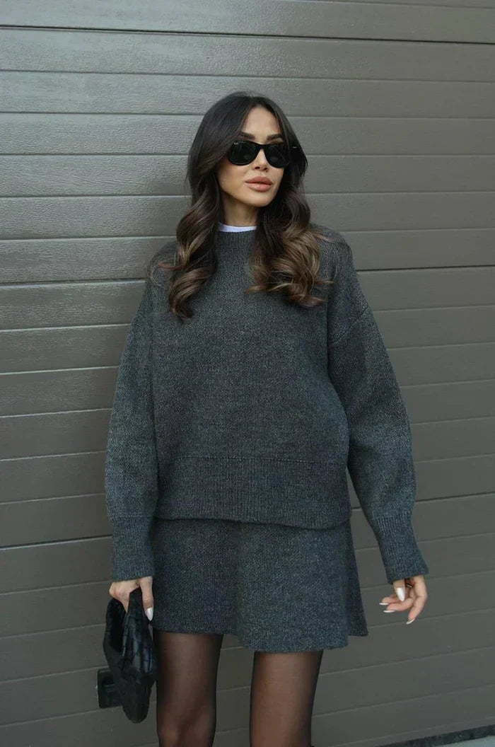 Anthrazitgraues Strickset in Frontansicht an einem Model, Pullover mit Rippbündchen und leicht ausgestellter Rock. 12