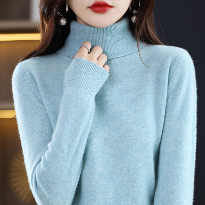 Hellblau melierter Rollkragenpullover am Model, eine Hand am Kragen, gerippte Ärmelbündchen gut sichtbar. 4