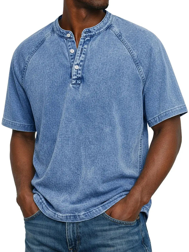 Mann trägt das Henley-Shirt mit Raglanärmeln in verwaschenem Hellblau, kombiniert mit Jeans, Frontansicht. 2