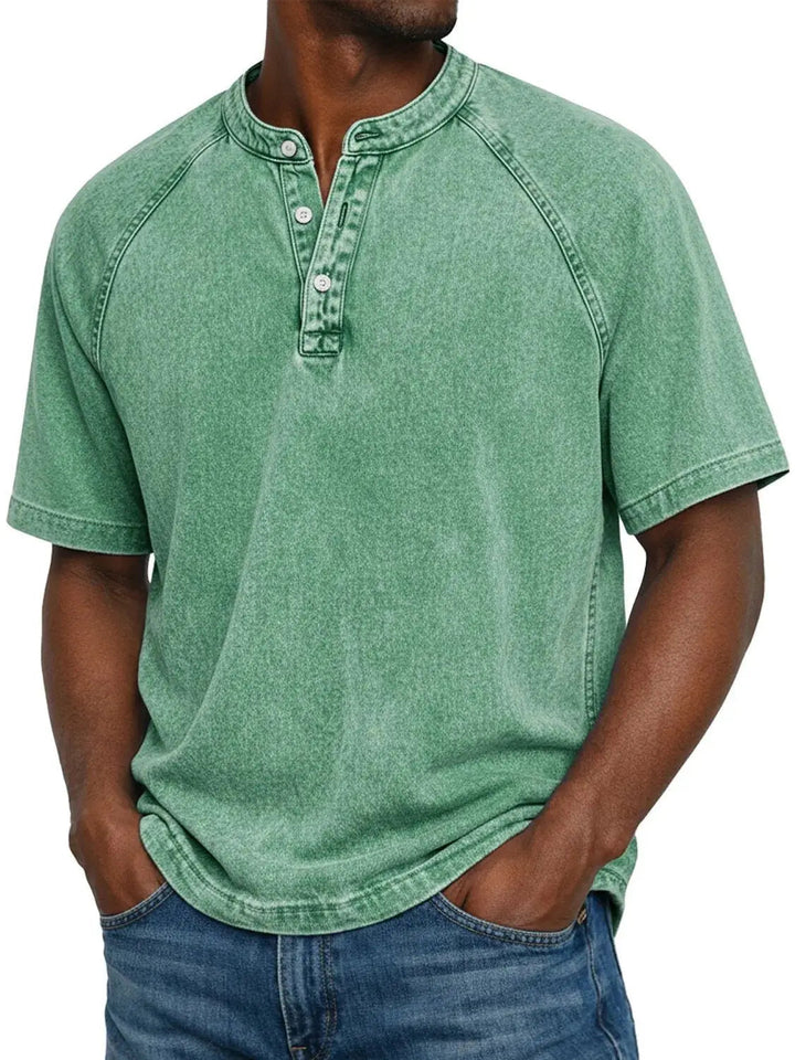 Mann trägt das Henley-Shirt mit Raglanärmeln in verwaschenem Hellgrün, Hände in den Taschen der blauen Jeans, Frontansicht. 6