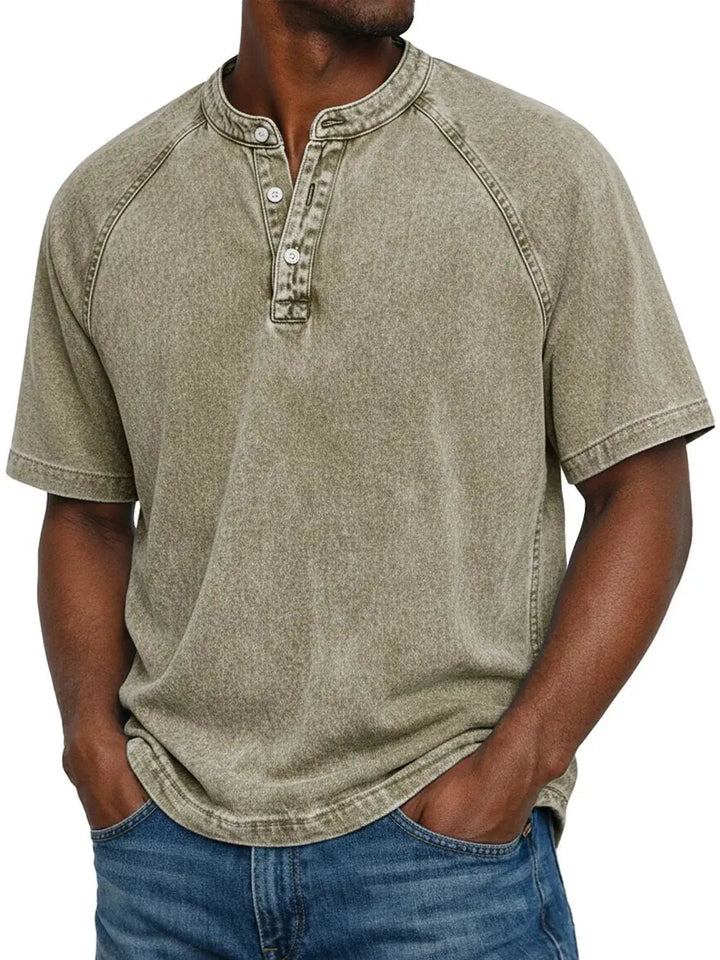 Mann trägt das Henley-Shirt mit Raglanärmeln in verwaschenem Khaki-Beige mit Knopfleiste, kombiniert mit Jeans, Frontansicht. 9