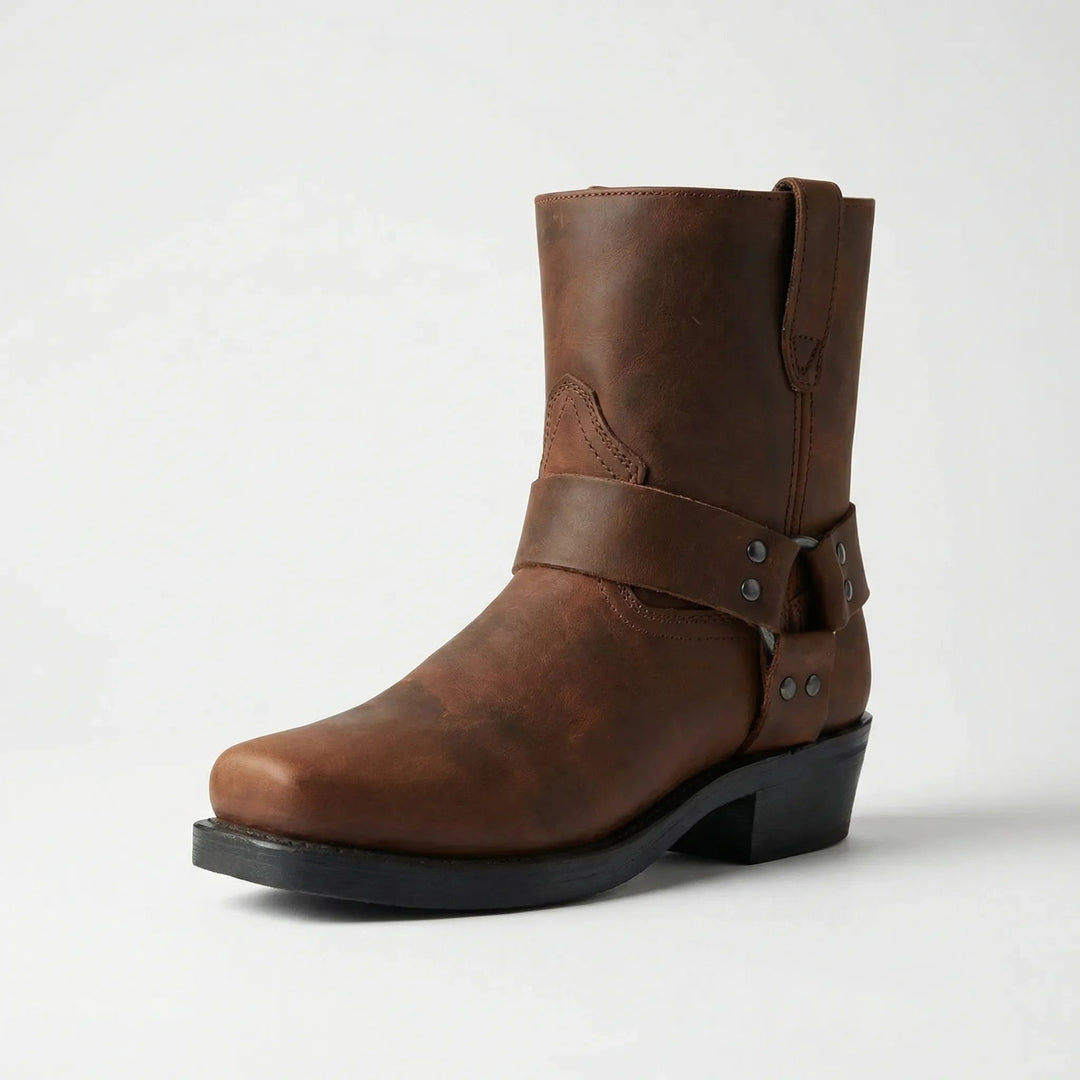 Brauner Lederstiefel mit Zierriemen und eckiger Spitze im Freisteller, leicht schräg von vorn aufgenommen. 4